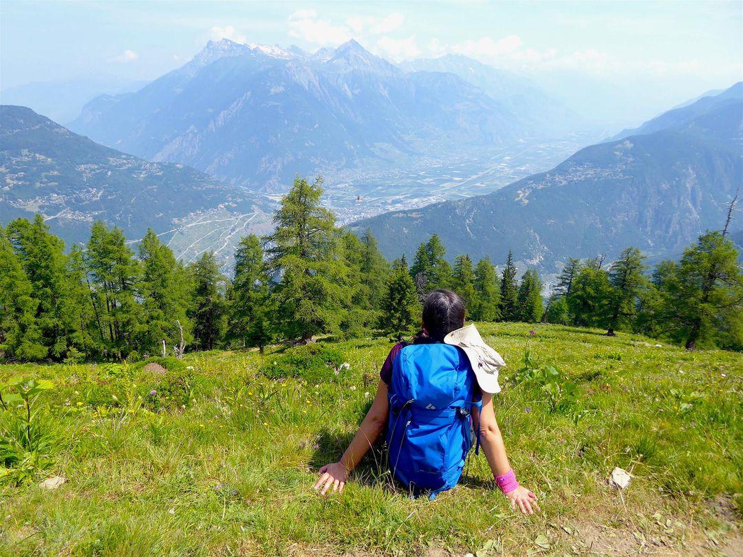 Tânia sentada no topo da montanha com vista para o vale